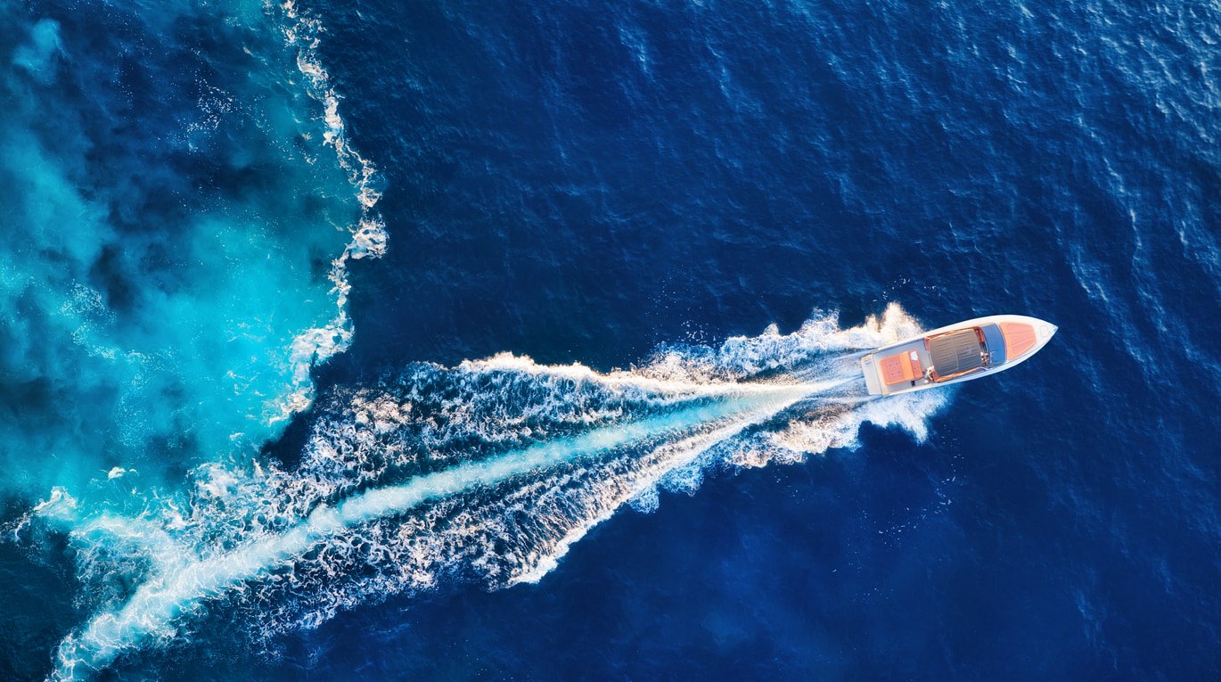 A birds-eye photo of a yacht going through the sea.