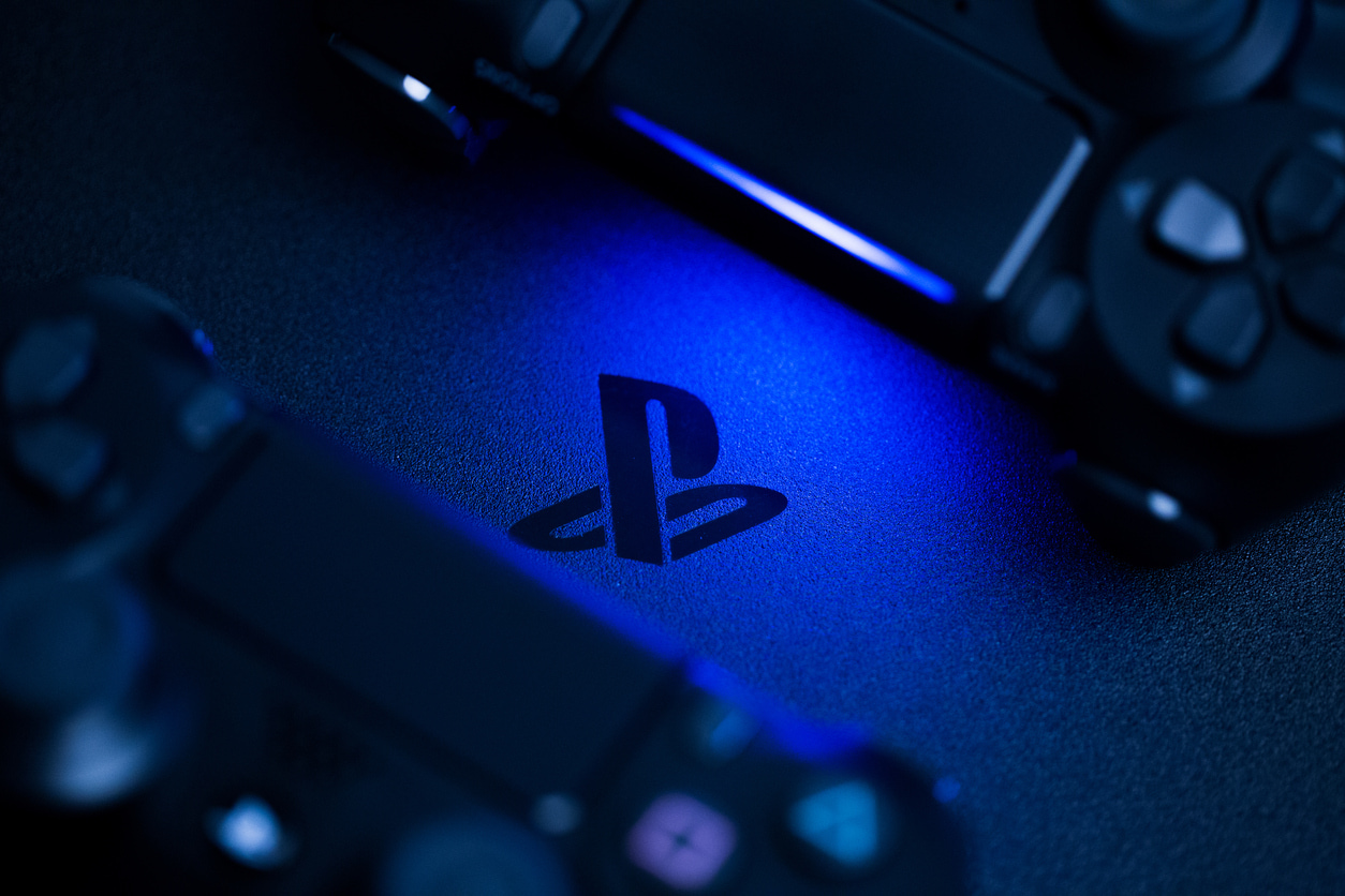 The Playstation logo being lit by a controller on a dark blue background.