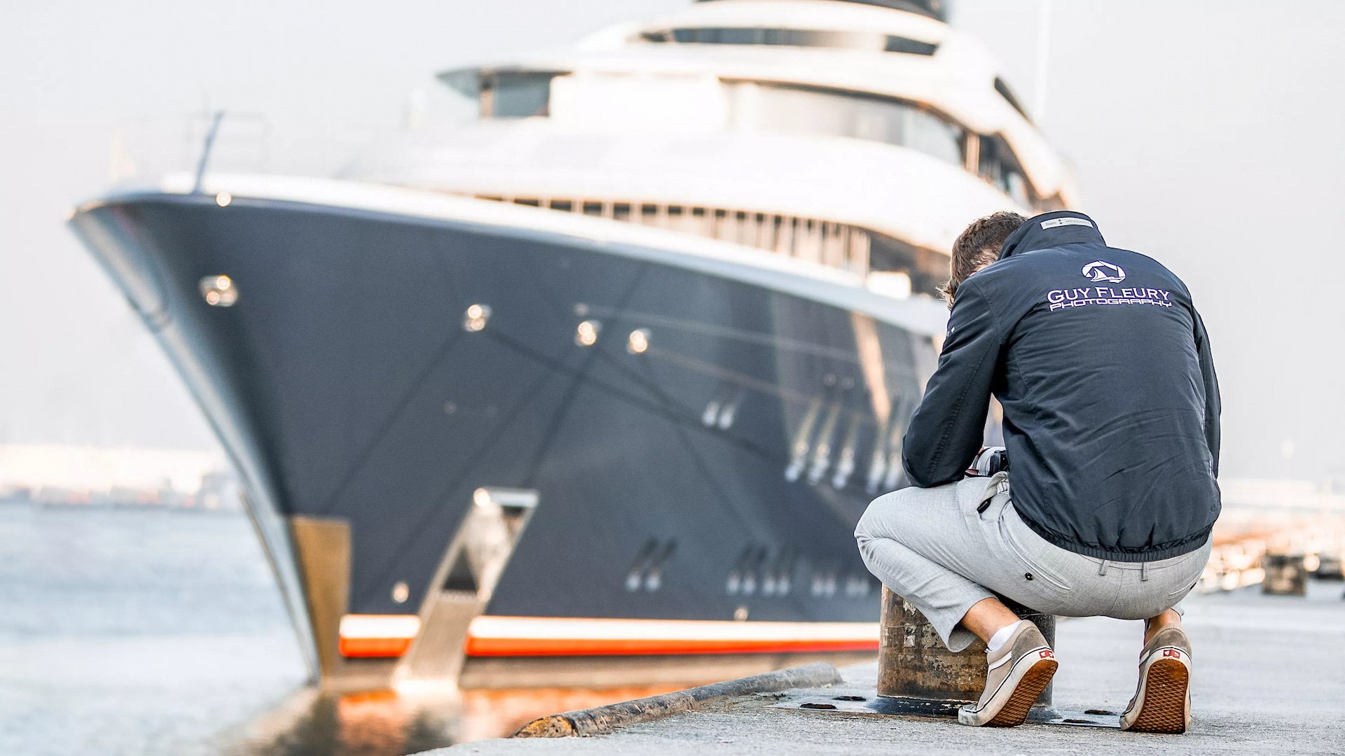 Photo of man looking disappointed with a yacht in the background.