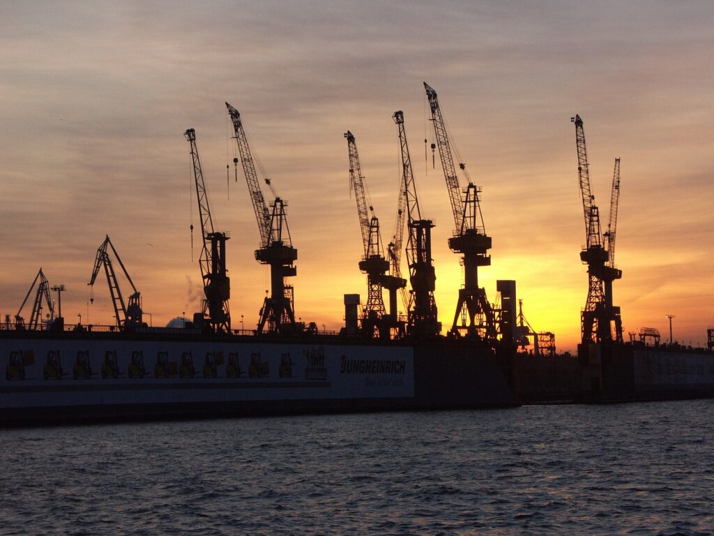 sunset behind shipyard of cranes