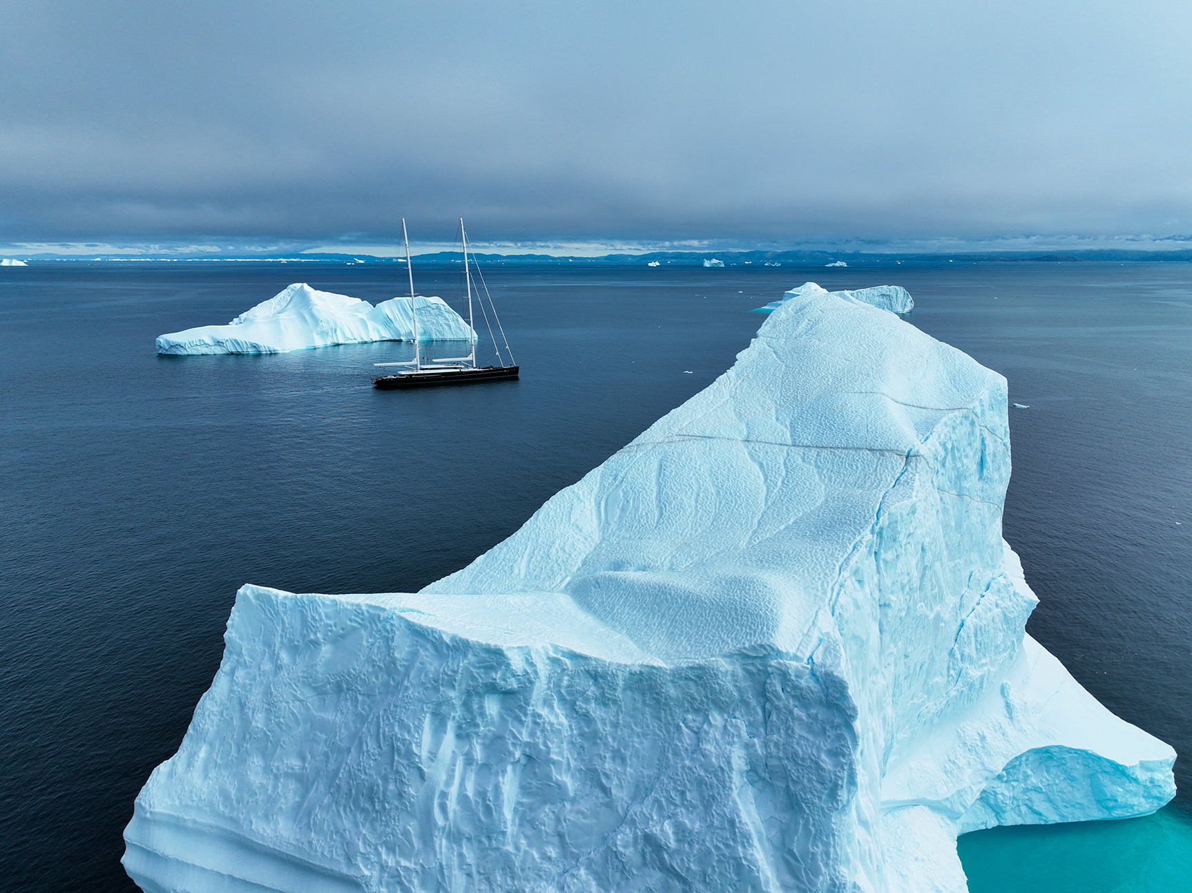 A superyacht in the water next to icebergs